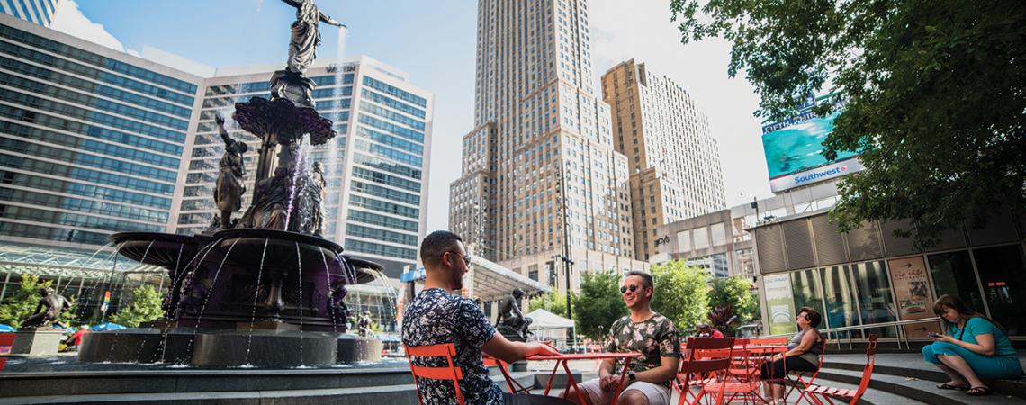 People sitting around a fountain outside of Carew Tower