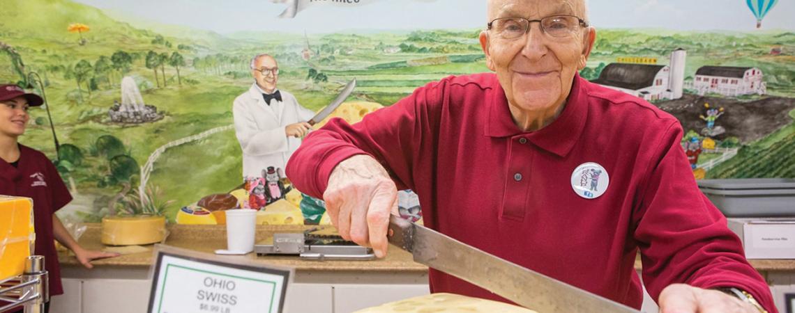 A man smiles with a giant block of cheese.