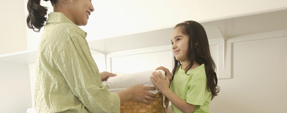 A woman and her daughter hold a basket of laundry.