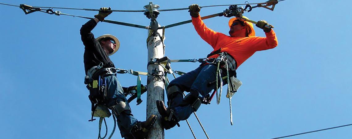 Two lineworkers work on a power line.