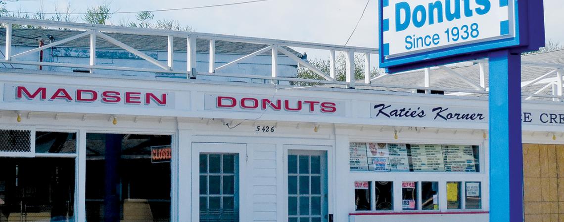 A picture of the outside of Madsen Donuts, featuring a large sign highlighting their history since 1938.