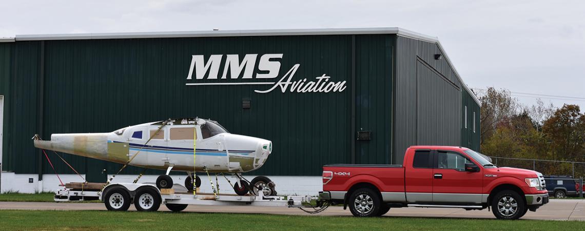 A truck pulls a small plane on a trailer outside of MMS Aviation.