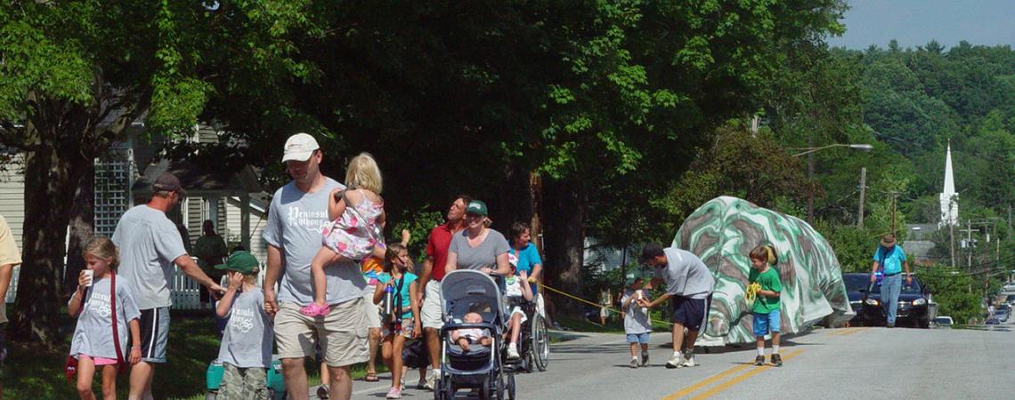 A small parade of children and parents walks down the street.