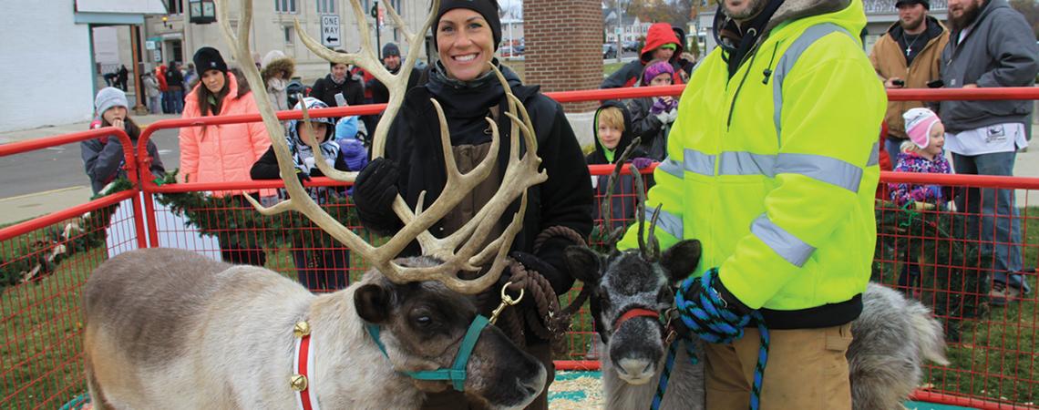 Nathan and Brienna Kleer smile with two reindeer.