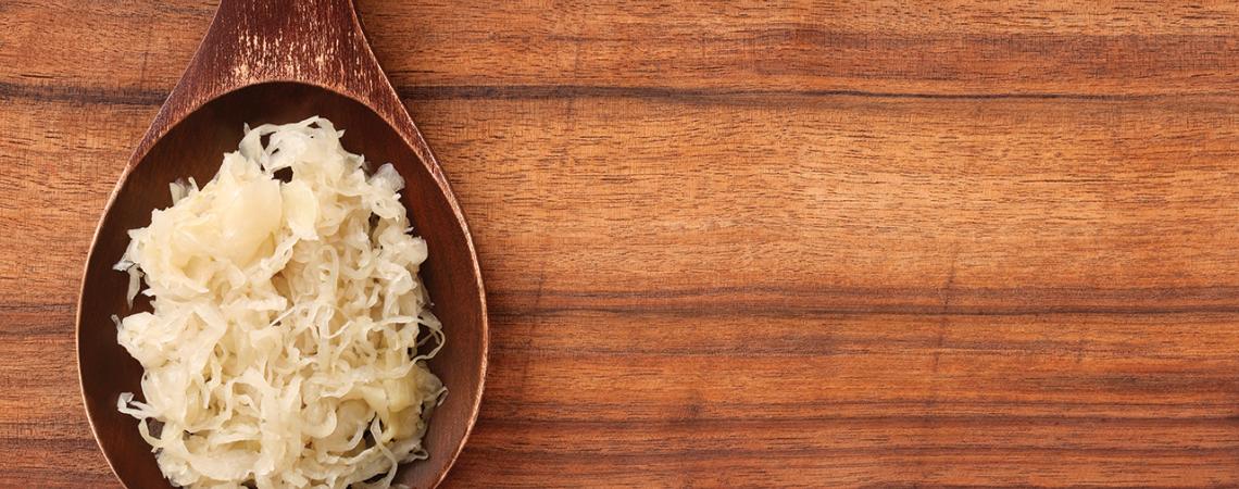 An image of sauerkraut on a wooden spoon.