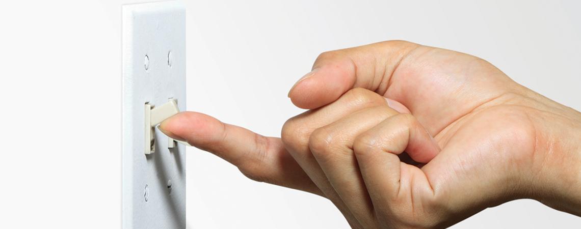 A hand flips on a light switch.