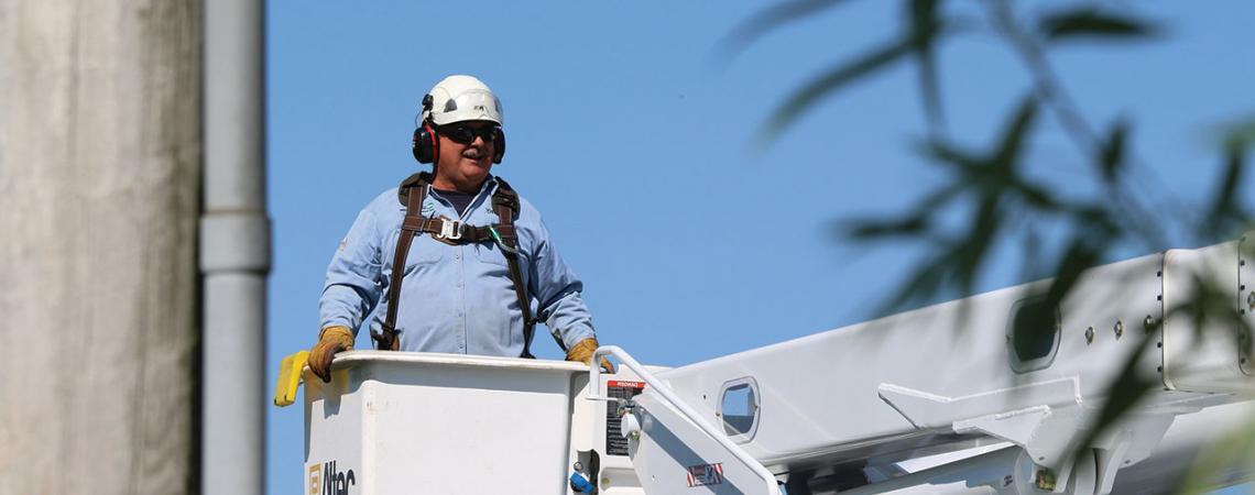 A lineworker stands in a bucket truck.