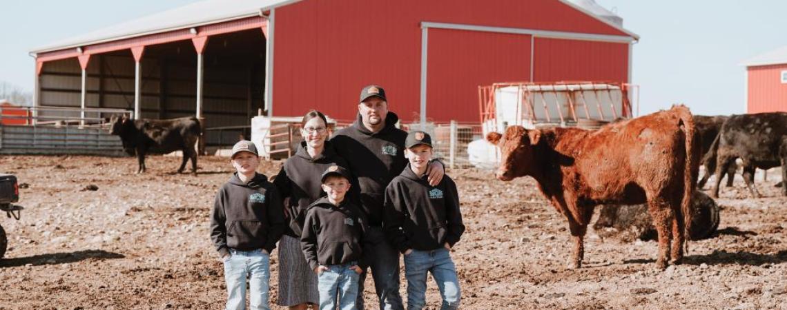 Co-op members posing in front of a pole barn built by the company their family owns and operates.