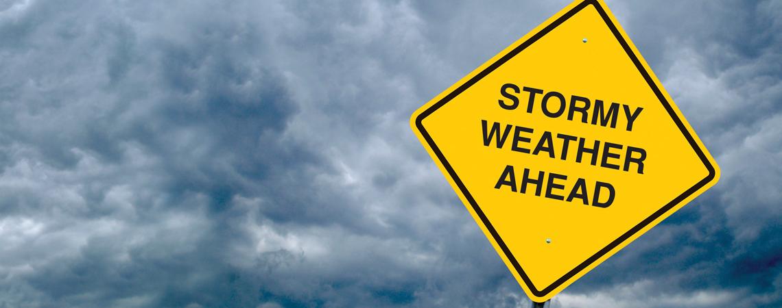 Stormy weather ahead sign in front of dark stormy sky background.