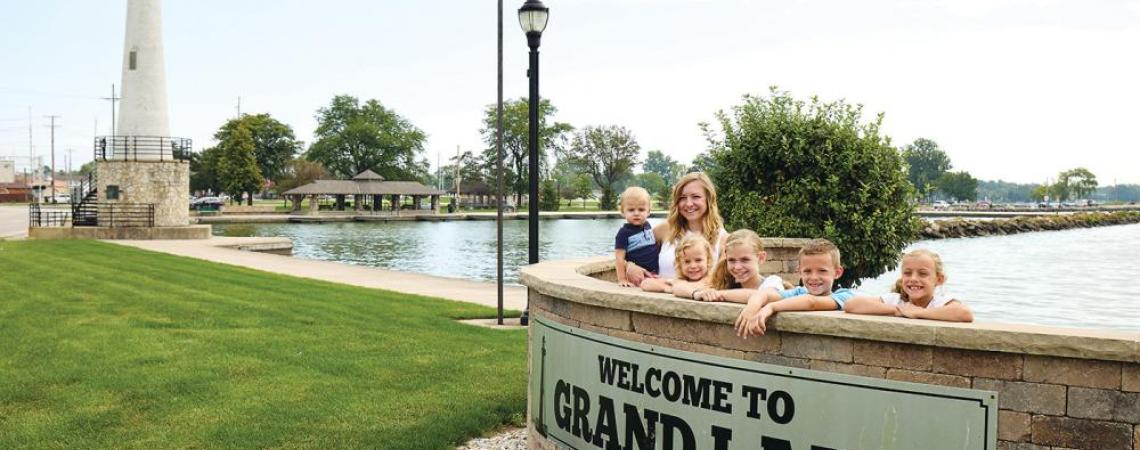 A family posing with the Grand Lake St. Marys sign. 