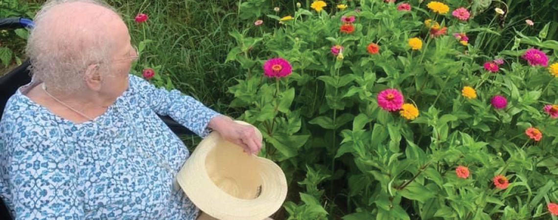 A resident of Woodland Country Manor enjoying flowers in the home's garden.