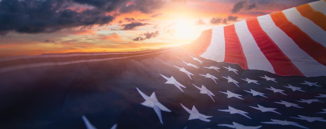 An American flag flying over a sunset
