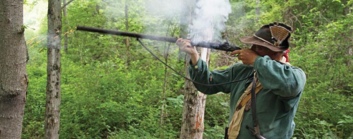 A person firing a muzzleloader