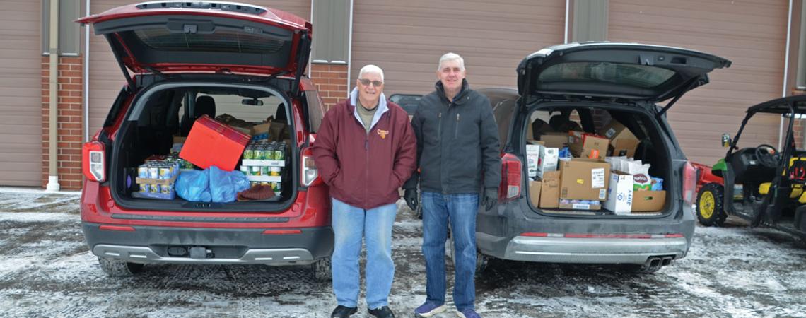 two people stand between cars filled with food