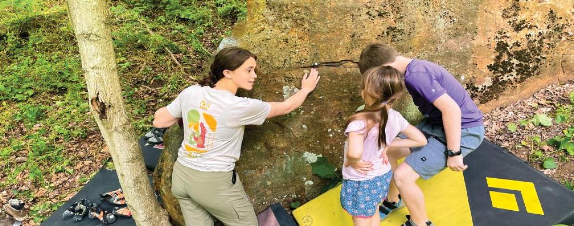 A woman talking to two kids about rock climbing