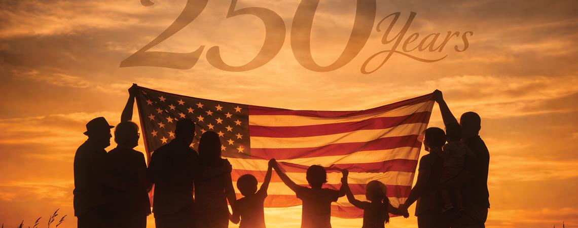 Silhouette of people holding the American flag at sunset