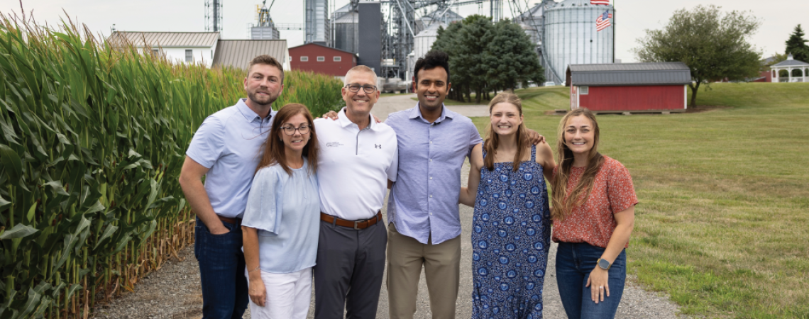 Vivek Ramaswamy posing with a group of people on a farm 
