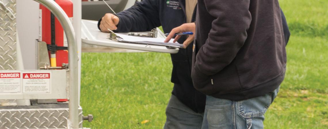 Two lineworkers reviewing paperwork beside a truck