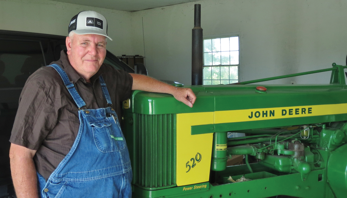 John Smiley posing with a John Deere tractor.